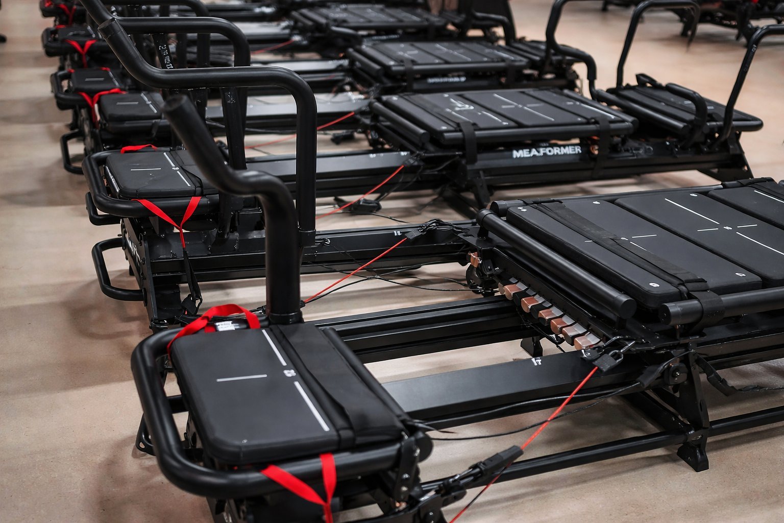 Row of black fitness equipment with red accents displayed on concrete floor in gym warehouse